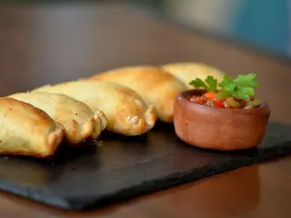 Media docena de empanadas doradas con salsa criolla
