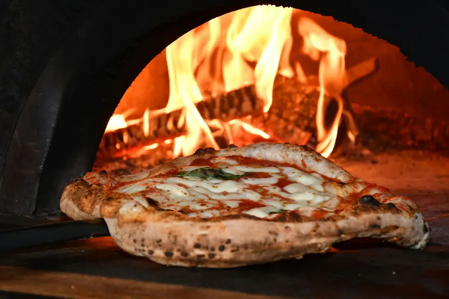 Pizza cocinándose en horno de leña